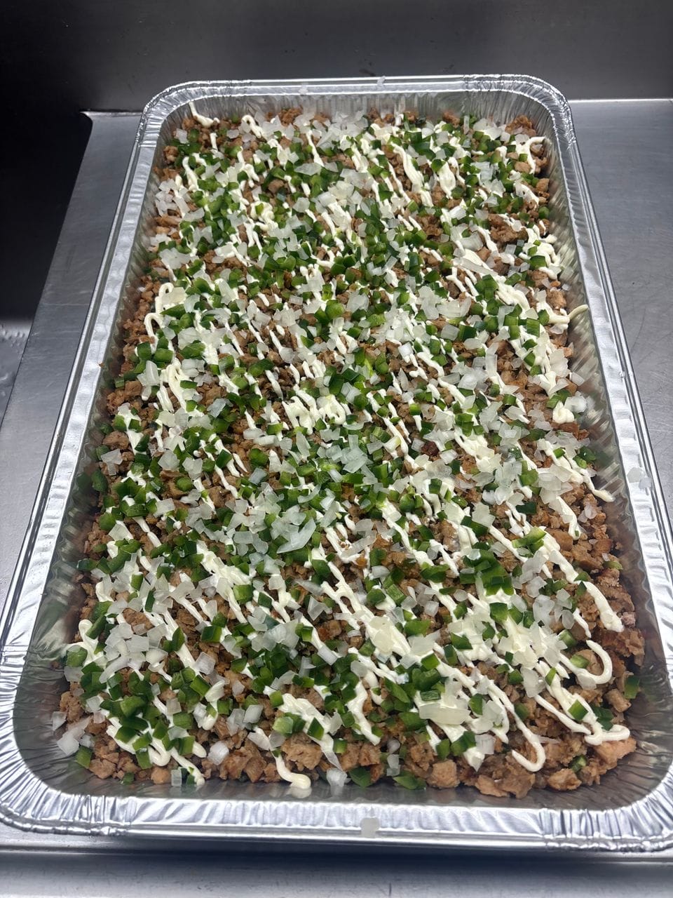 A full pan of loaded fries with seasoned beef, onion and sauce